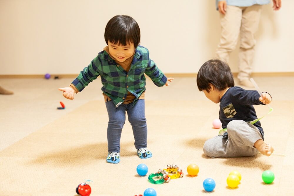 ニコットミュージック瑞江教室の絨毯のレッスンルームで子ども2人がボールで遊んでいる写真。